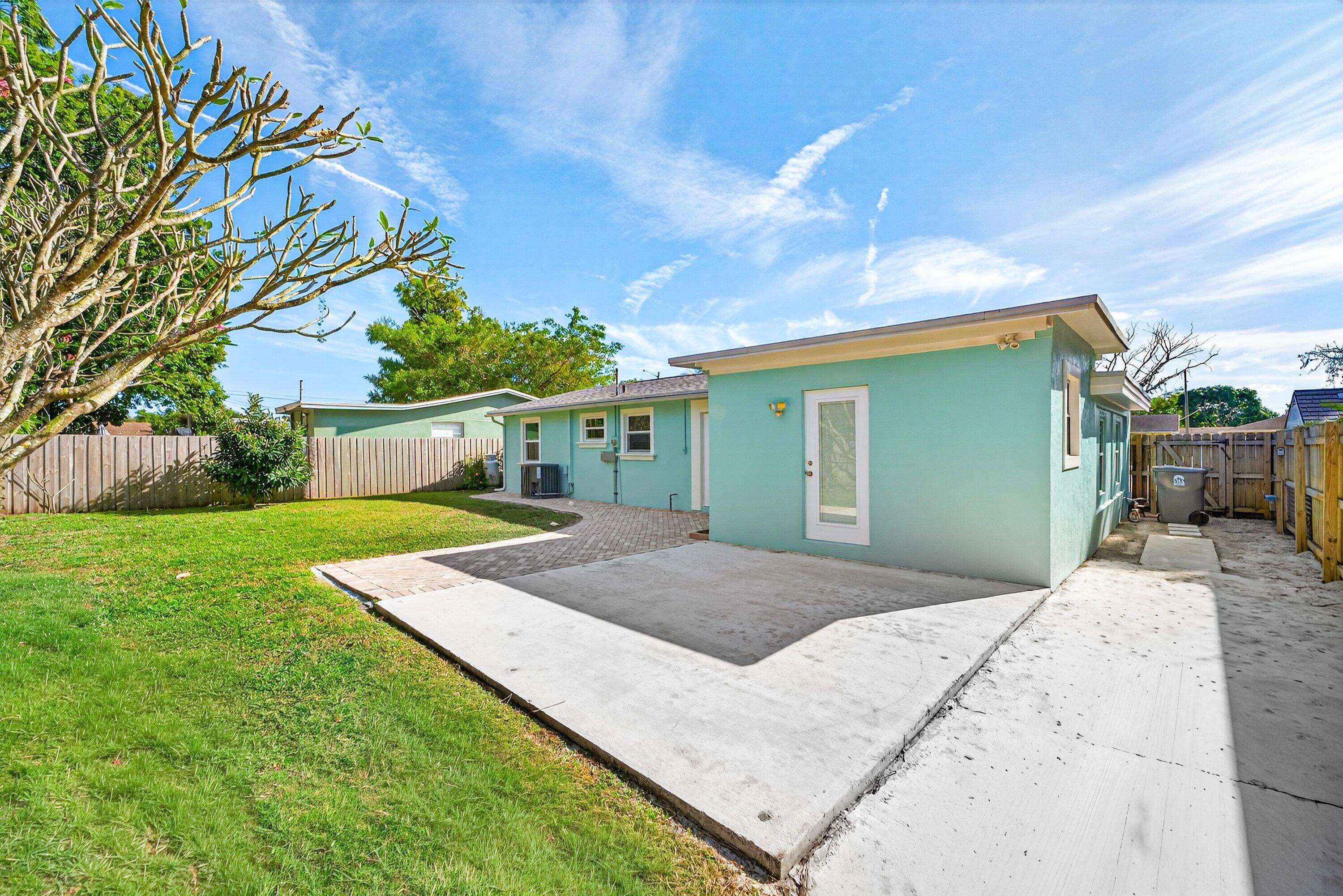 5565 Papaya Road Royal Palm Estates, FL 33413 - Photo 28 of 30 a view of yellow house with a big yard and potted plants