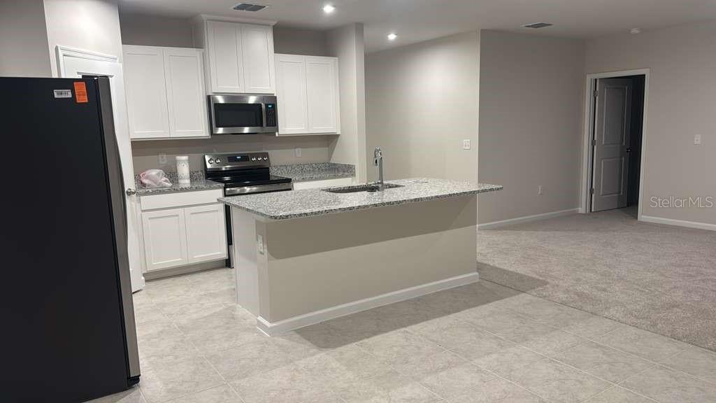 347 Biltmore Boulevard Dundee, FL 33838 - Photo 5 of 18 a kitchen with stainless steel appliances a stove a sink a refrigerator a microwave and cabinets