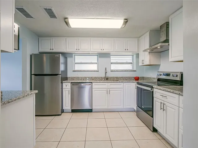 a kitchen with granite countertop a sink stove and refrigerator