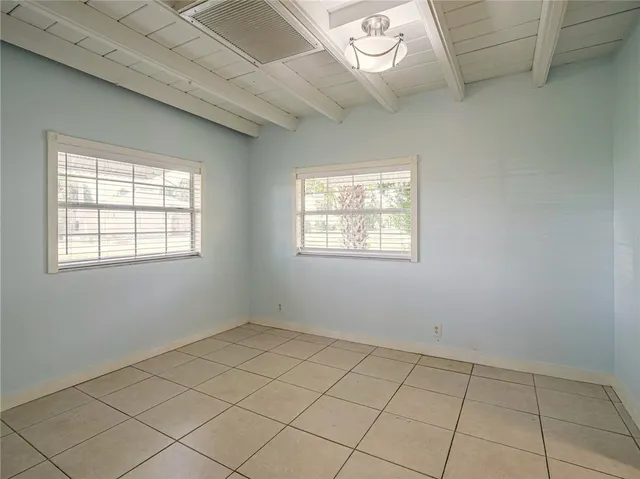 a view of an empty room with wooden floor and windows