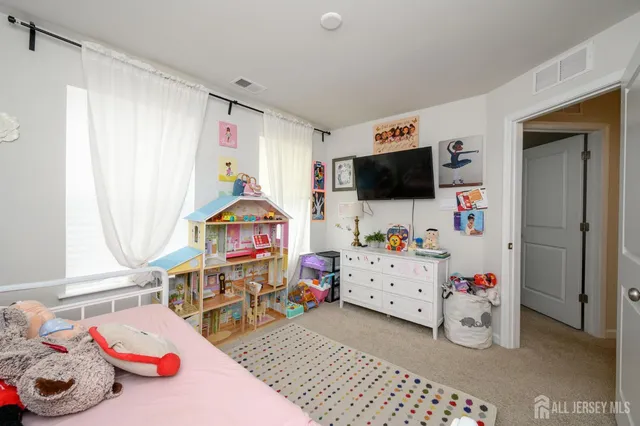 a room with a baby bed a couch and a window