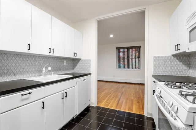 a kitchen with granite countertop a sink a stove and cabinets