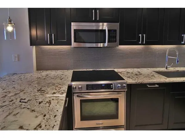 a kitchen with granite countertop a stove top oven microwave and fridge