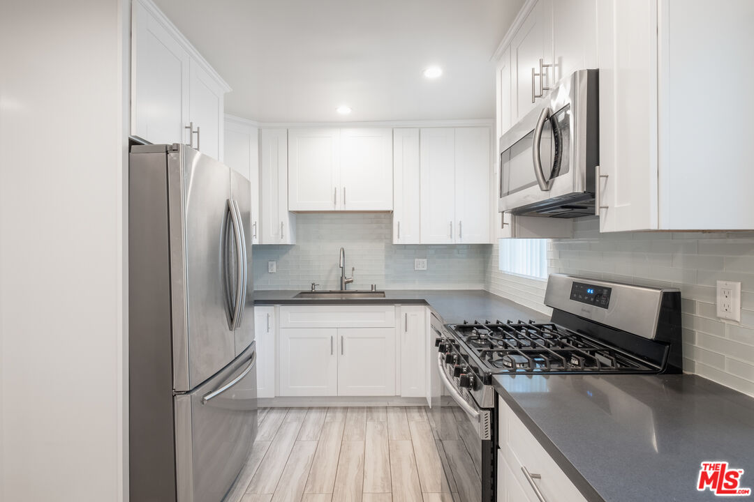 1024 Maple Street, Unit 1 Santa Monica, CA 90405 - Photo 5 of 16 a kitchen with stainless steel appliances granite countertop a refrigerator stove sink and cabinets