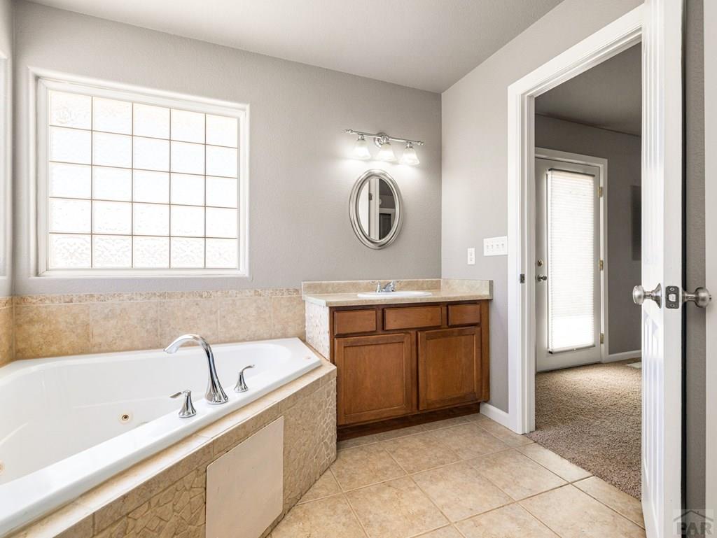 43948 Hunsaker Road Avondale, CO 81022 - Photo 23 of 56 a bathroom with a tub a sink and a large mirror