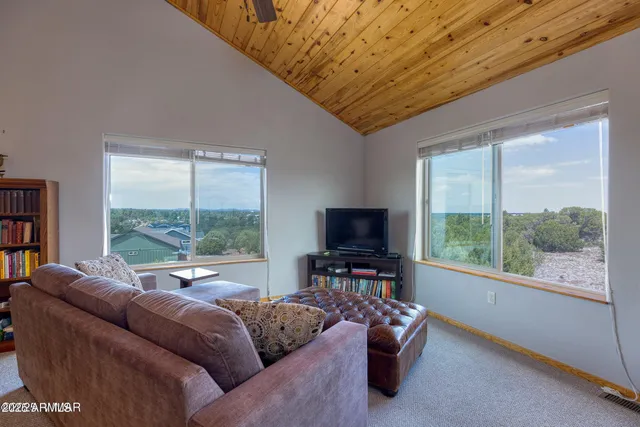 a living room with furniture a flat screen tv and a floor to ceiling window