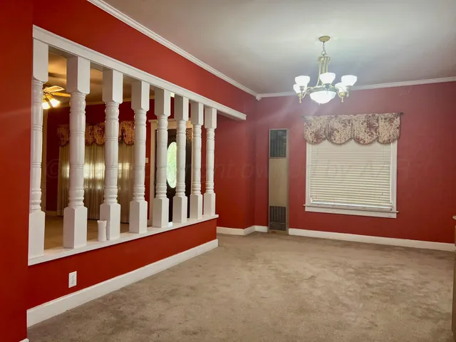 a view of an empty room with chandelier fan and a window