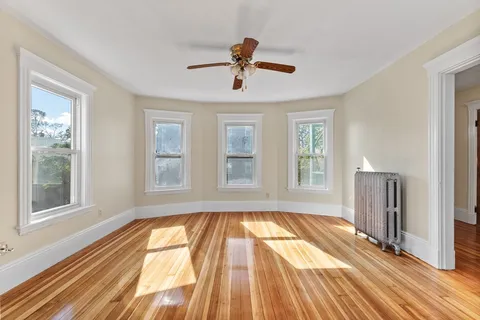 a view of empty room with wooden floor and fan