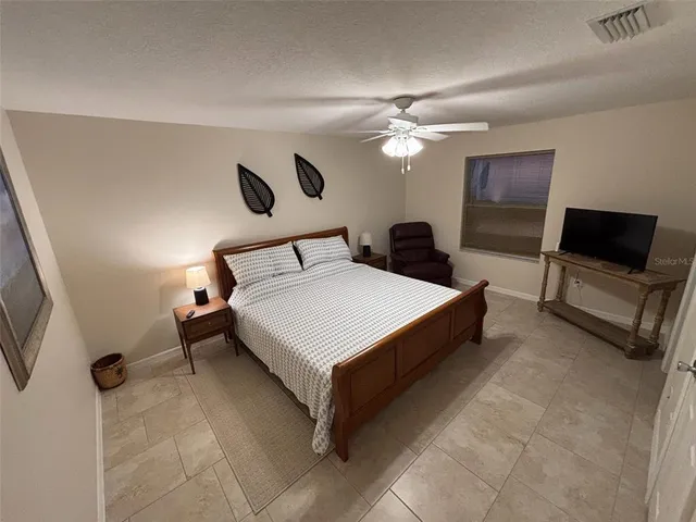 a spacious bedroom with a bed and a flat screen tv