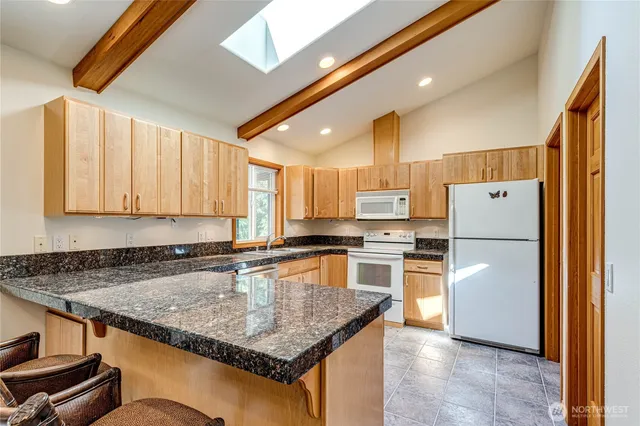 a kitchen with stainless steel appliances granite countertop a refrigerator a stove and a sink