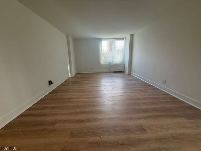 1 Claridge Drive, Unit 428 Verona, NJ 07044 - Photo 15 of 17 a view of an empty room with wooden floor and window