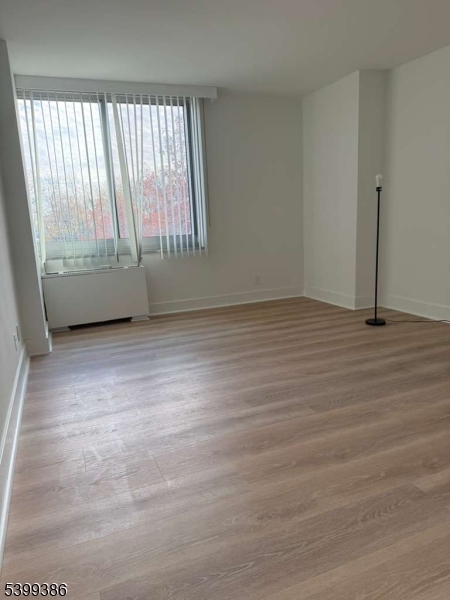 1 Claridge Drive, Unit 428 Verona, NJ 07044 - Photo 3 of 17 an empty room with wooden floor and windows