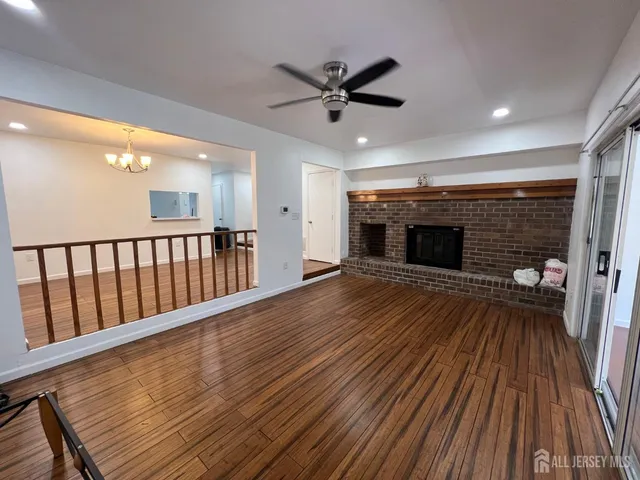 a view of a livingroom with a fireplace wooden floor and a ceiling fan