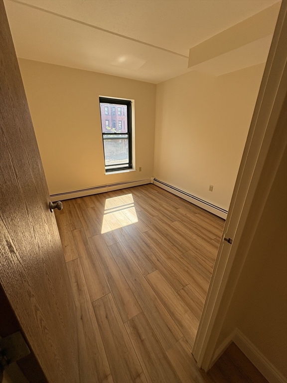 400 Massachusetts Avenue, Unit 34 Boston, MA 02115 - Photo 13 of 24 a view of an empty room with wooden floor and a window