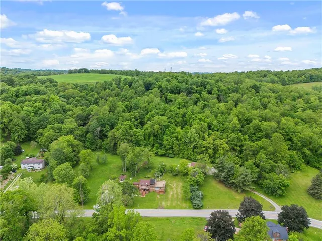 an aerial view of residential house with outdoor space and trees all around