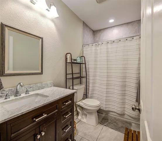 a bathroom with a sink a toilet a mirror and shower curtain