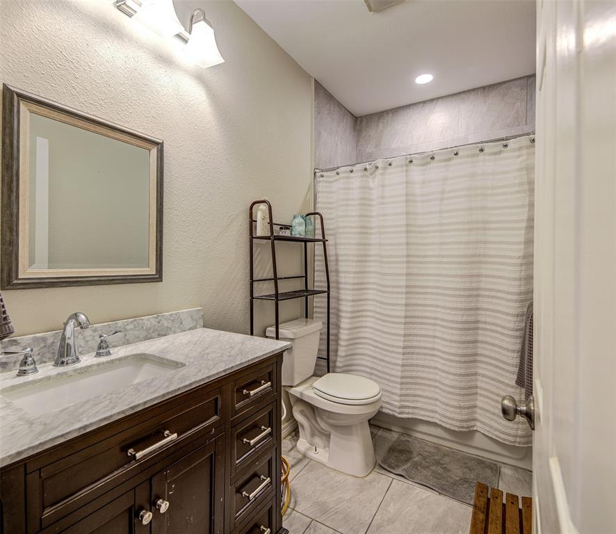 308 Cooke Street Nocona, TX 76255 - Photo 14 of 22 a bathroom with a sink a toilet a mirror and shower curtain