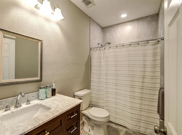 a bathroom with a granite countertop sink toilet and shower