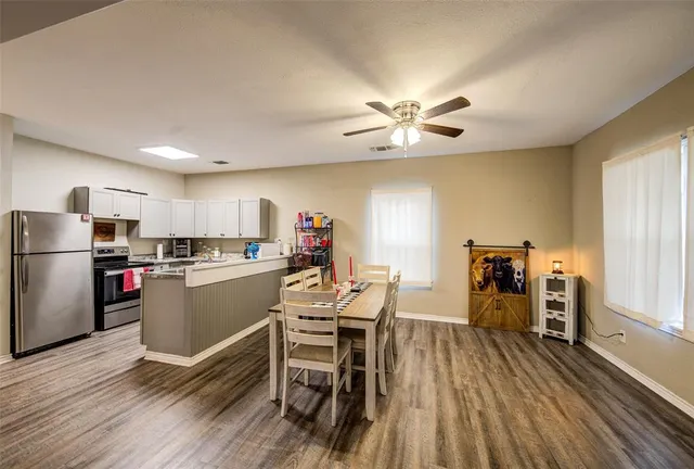 a dining room with furniture a kitchen wooden floor and a window