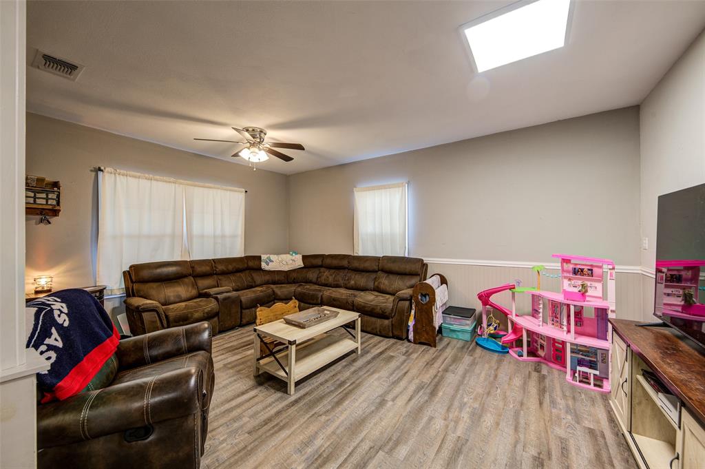 308 Cooke Street Nocona, TX 76255 - Photo 9 of 22 a living room with furniture a flat screen tv and gym equipment