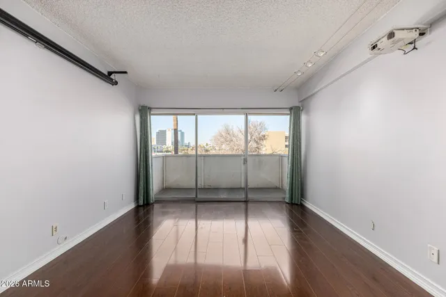 a view of an empty room with wooden floor and a window