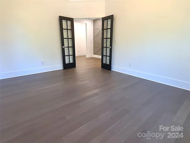 an empty room with wooden floor and natural light