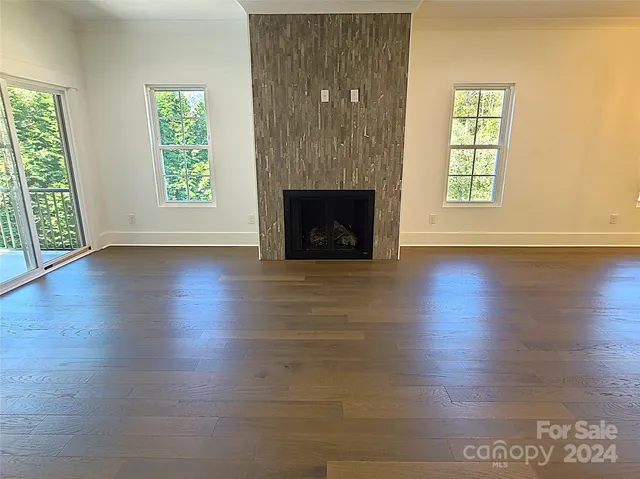 an empty room with wooden floor a fireplace and windows