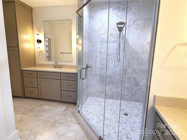 a bathroom with a granite countertop sink a mirror and shower
