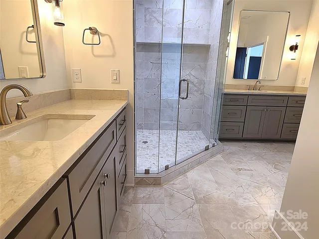 a bathroom with a granite countertop sink a mirror and shower
