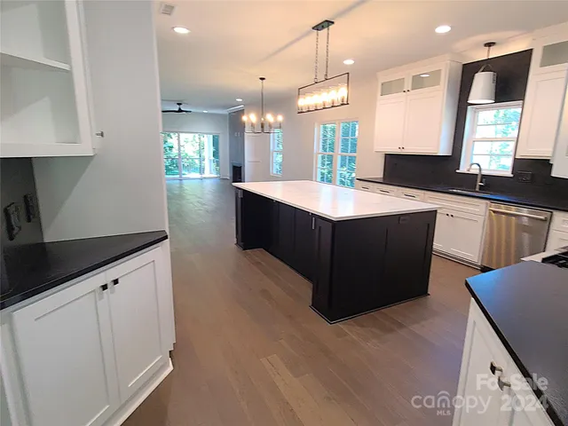 a large kitchen with a large counter top space a sink stainless steel appliances and cabinets