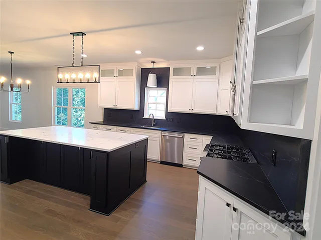 a kitchen with stainless steel appliances granite countertop a sink a stove and a wooden floors