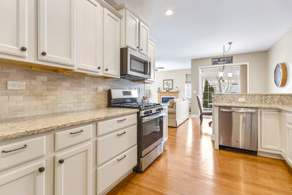 1093 Glendale Road Pingree Grove, IL 60140 - Photo 9 of 28 a kitchen with stainless steel appliances granite countertop white cabinets a sink a stove a dining table and chairs