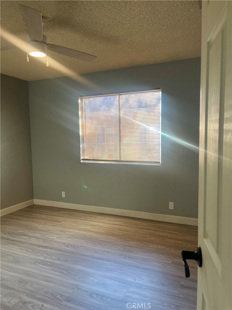 16535 Pine Street, Unit B Hesperia, CA 92345 - Photo 18 of 22 an empty room with wooden floor and windows