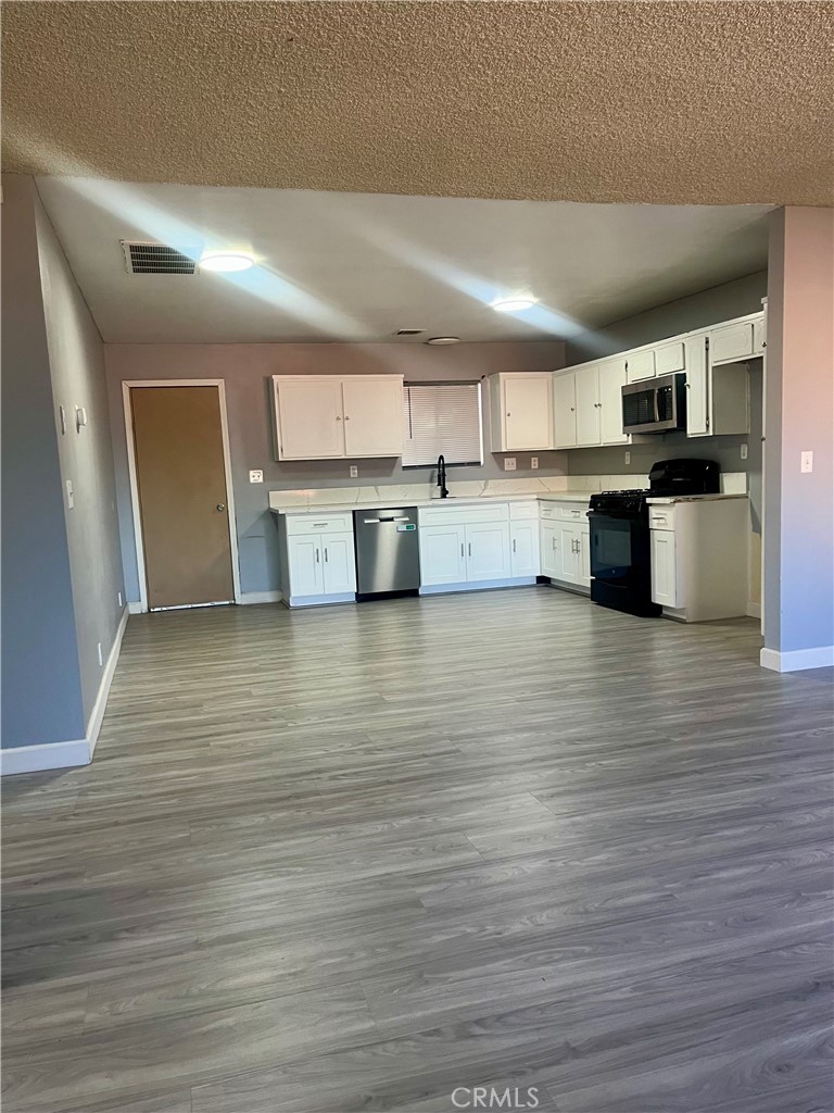 16535 Pine Street, Unit B Hesperia, CA 92345 - Photo 9 of 22 a kitchen with stainless steel appliances wooden cabinets and a wooden floor