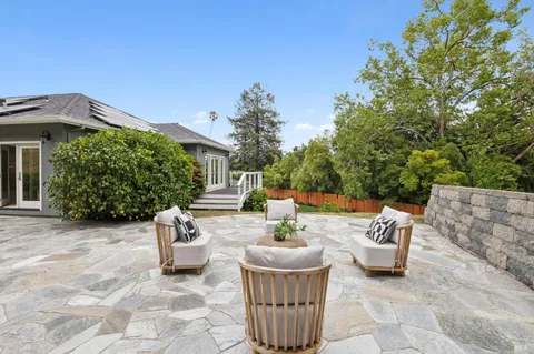 a view of a backyard with sitting area and tree