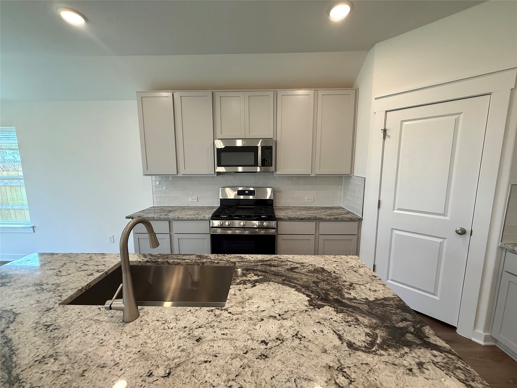 13605 Barn Chime Street Elgin, TX 78621 - Photo 4 of 20 a kitchen with granite countertop a sink and a stove top oven