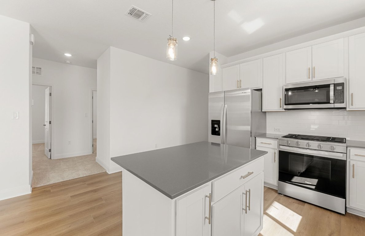 100 Eagle Valley Drive Elgin, TX 78621 - Photo 3 of 7 a kitchen with stainless steel appliances a stove microwave and refrigerator