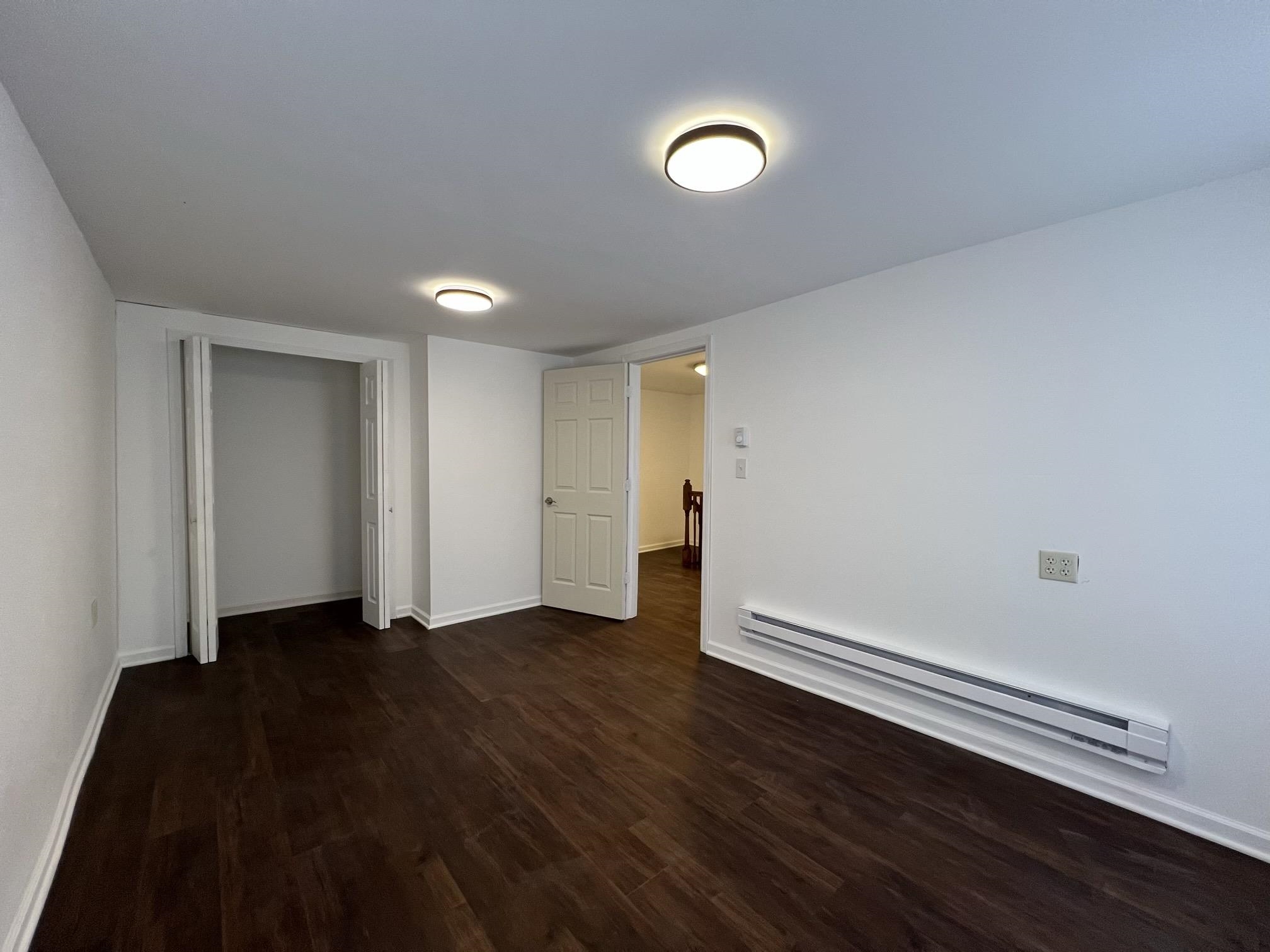 306 7th Street West Ashland, WI 54806 - Photo 12 of 25 Unfurnished bedroom with a baseboard heating unit, dark wood finished floors, and a closet