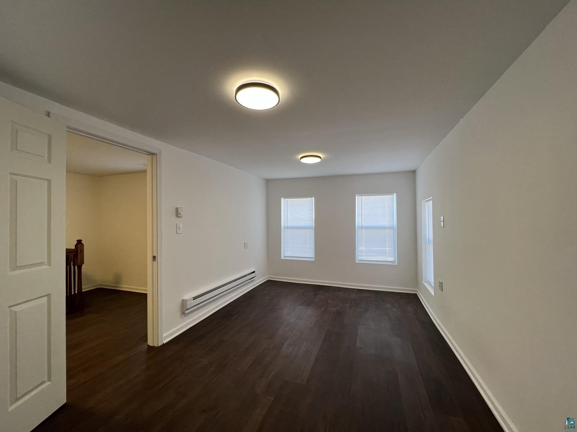 306 7th Street West Ashland, WI 54806 - Photo 13 of 25 Empty room featuring dark wood-style flooring and a baseboard heating unit