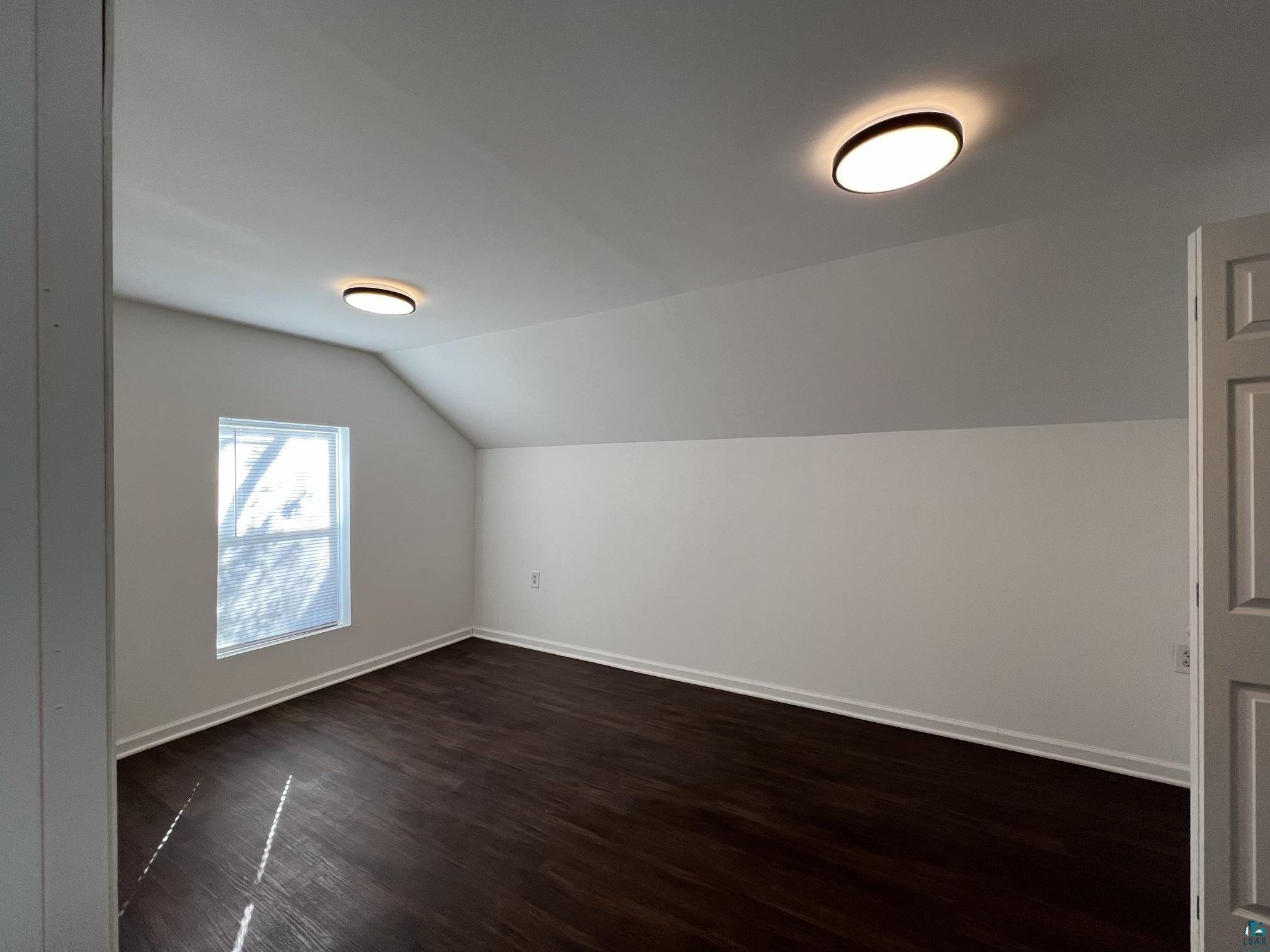 306 7th Street West Ashland, WI 54806 - Photo 21 of 25 Additional living space with dark wood finished floors and vaulted ceiling