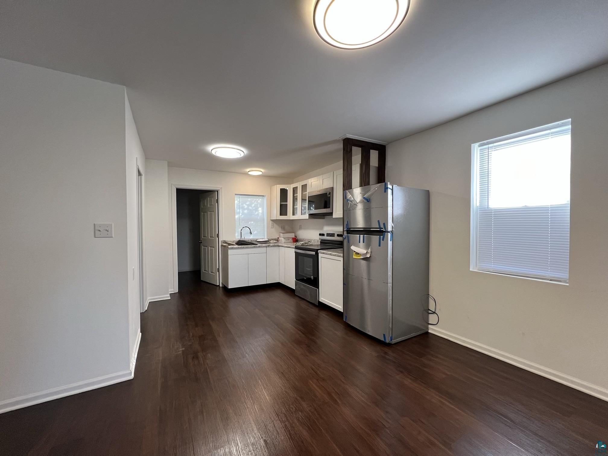 306 7th Street West Ashland, WI 54806 - Photo 4 of 25 Kitchen with glass insert cabinets, white cabinetry, stainless steel appliances, and dark wood-style flooring