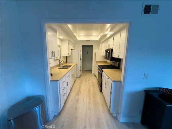 a view of a kitchen with wooden floor and a sink