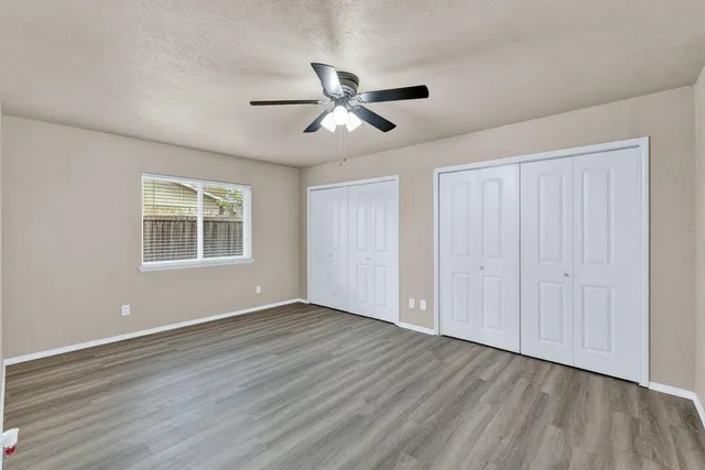 a view of empty room with wooden floor and fan