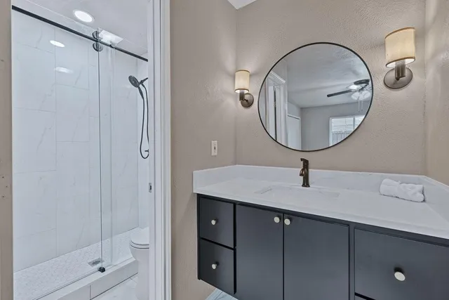 a bathroom with a granite countertop sink a mirror and shower