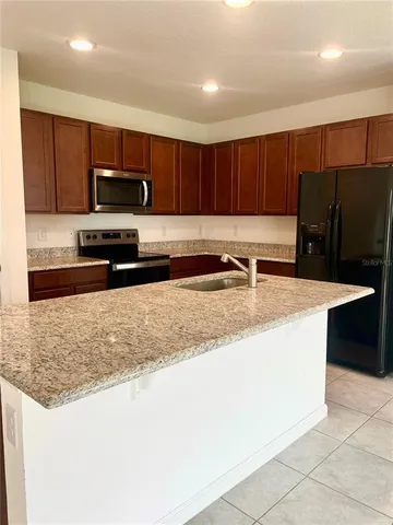 a kitchen with stainless steel appliances granite countertop a sink a stove a microwave and a refrigerator