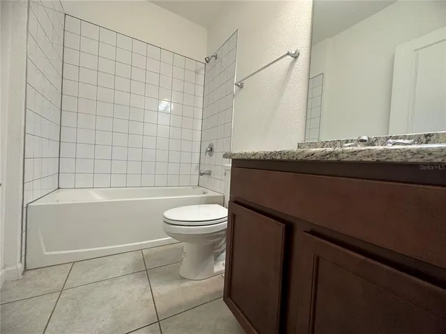 a bathroom with a granite countertop bathtub shower sink and toilet