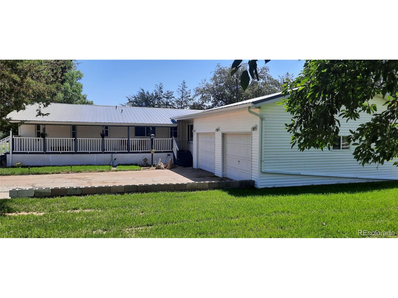 a view of a white house with a big yard and potted plants