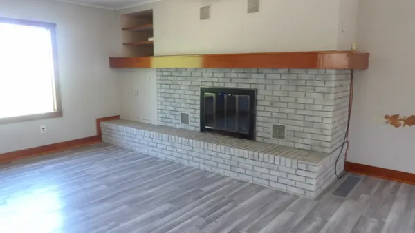 an empty room with wooden floor and fireplace