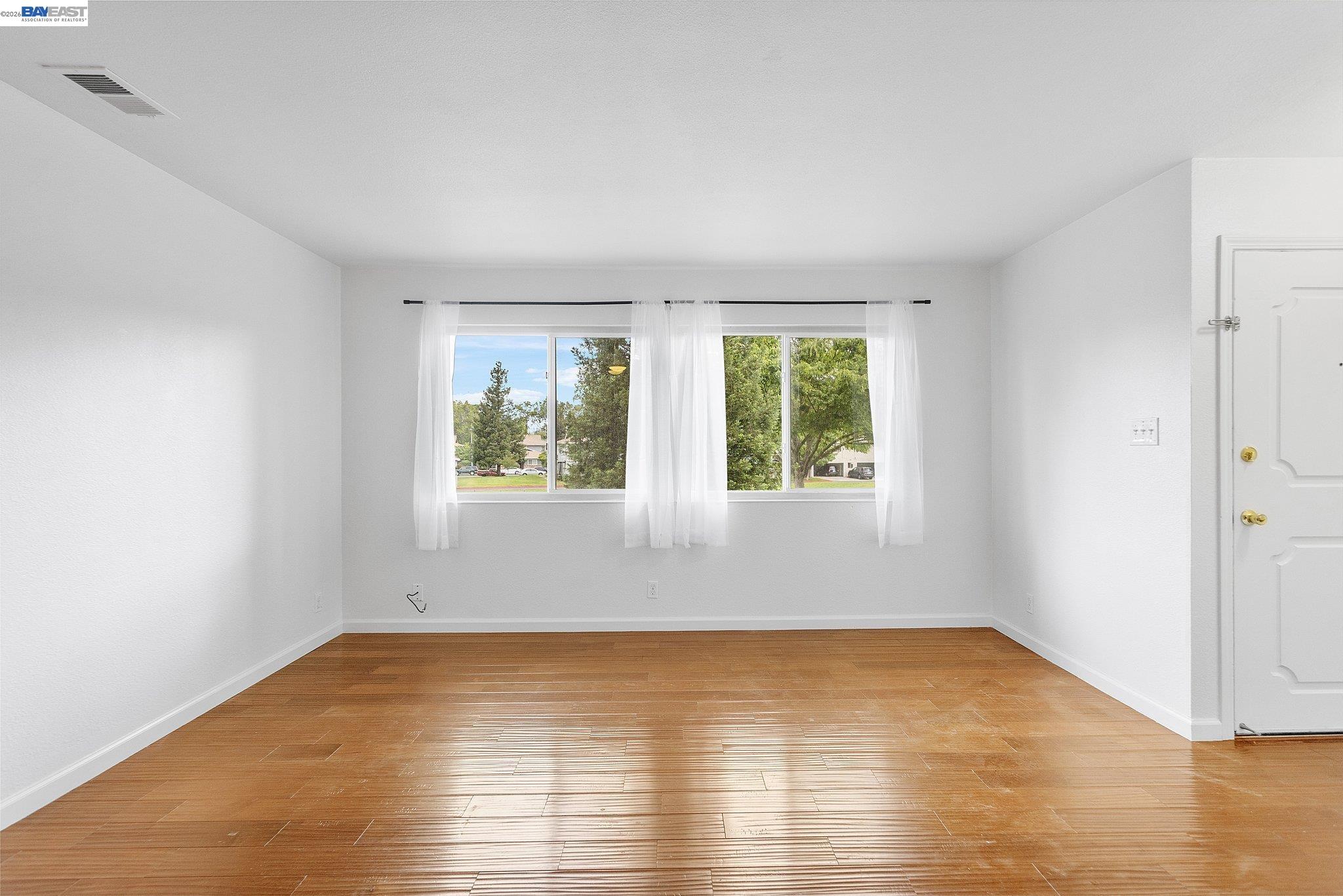 an empty room with wooden floor and windows