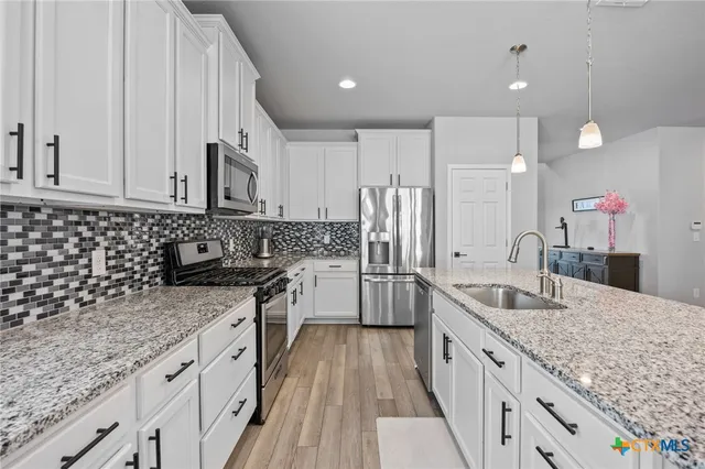 a kitchen with stainless steel appliances granite countertop a sink stove and refrigerator
